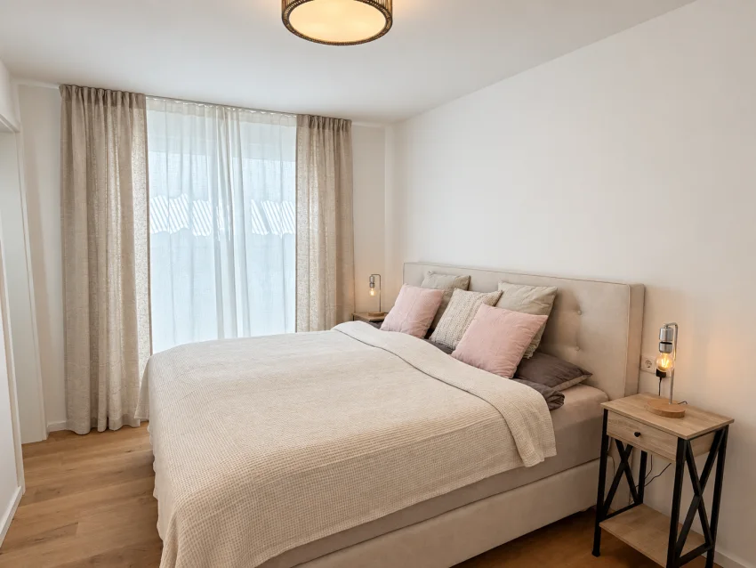 Schlafzimmer im Souterrain mit großem Bett und hellen Textilien
